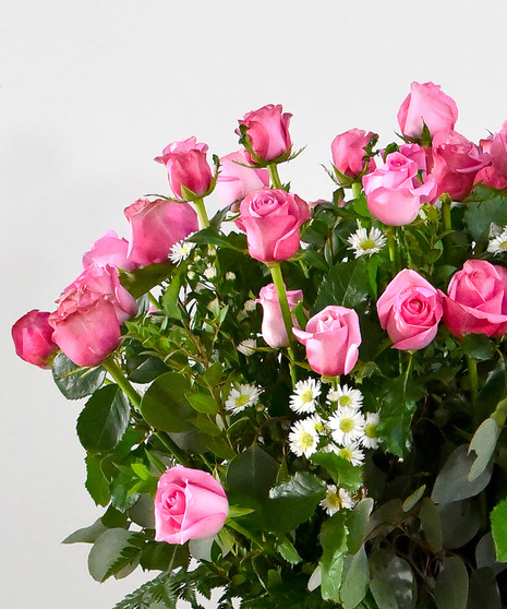 Blushing pink roses are accented with lovely green foliage in a glass vase will make anyone’s heart melt. 