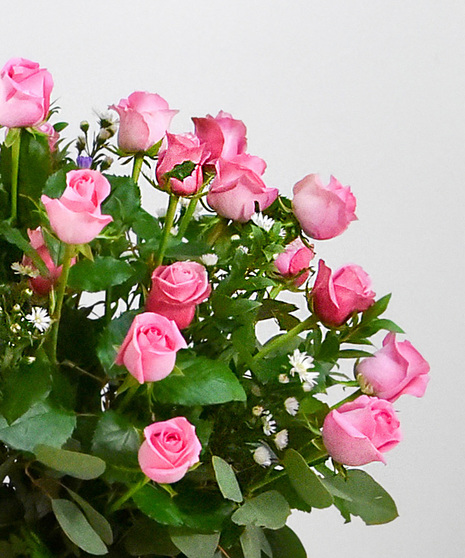 Blushing pink roses are accented with lovely green foliage in a glass vase will make anyone’s heart melt. 